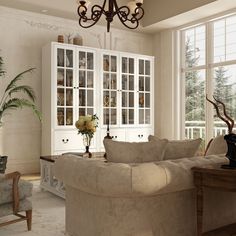 a living room filled with furniture and a chandelier hanging from the ceiling next to a window