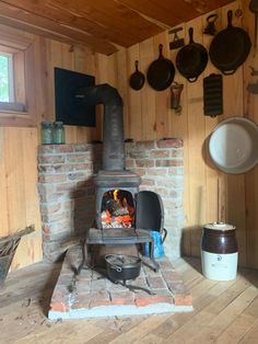 a wood burning stove in a wooden room with pots and pans hanging on the wall