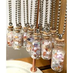 several glass bottles filled with different types of beads and chains hanging from a metal rod