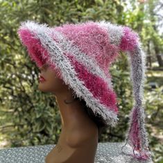 Add this gorgeous one of a kind fuzzy pink witch hat to your accessories for your next festival, holiday party or cosplay event.  You'll be the envy of all your witchy friends when you walk into a room.  Beautifully crafted in a double thickness with a soft texture that you will fall in love with.  Brim can be left down or rolled up. Created with gray acrylic yarn and a variety of pink eyelash yarn. Hand wash gently with a mild detergent and lay flat to dry. 25" from brim to tip before fringe (f Whimsical Pink Costume Hats And Headpieces For Carnival, Pink Whimsical Costume Hats For Carnival, Whimsical Pink Costume Hats For Carnival, Pink Brimmed Costume Hat For Winter, Adjustable Pink Halloween Costume Hats And Headpieces, Adjustable Pink Halloween Costume Hat, Adjustable Pink Costume Hat For Halloween, Pink Brimmed Winter Costume Hat, Pink Winter Costume Hats And Headpieces