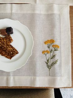 a white plate topped with food next to a flower on top of a cloth covered table