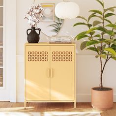 a yellow cabinet sitting next to a potted plant