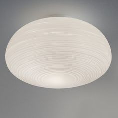 a white ceiling light hanging from the ceiling in a room with grey walls and flooring