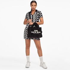 A luxurious style that accommodates all your everyday necessities, The Medium Tote by Marc Jacobs is crafted from black terry, adorned with the brand's unique lettering on the front in a striking white contrast. Providing a variety of styling possibilities, the bag features both top handles and a cross-body strap for convenience..Black and white terry.Detachable shoulder strap, top handles, designer patch.Internal zipped pocket, two slip pockets, card slot.Zip closure.Dimensions: H: 27cm x W: 34cm x D: 15cm. Handle drop: 12cm. Strap drop: 69cm. Casual Black Bags With Logo Print, Trendy Black Bags With Logo Print, Unique Lettering, Tan Bag, Beige Bag, Buy Bags, Branding Coach, Small Tote Bag, The Medium