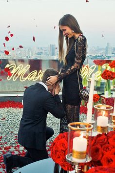 a man kneeling down next to a woman on top of a table covered in flowers