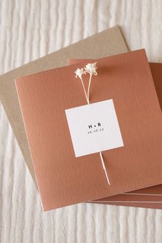 two cards with flowers on them sitting next to each other in front of a bed