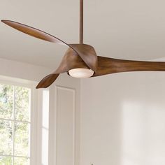 a ceiling fan that is hanging from the ceiling in a room with white walls and windows