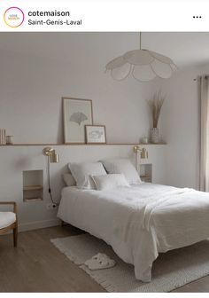 a white bed sitting in a bedroom on top of a hard wood floor next to a window