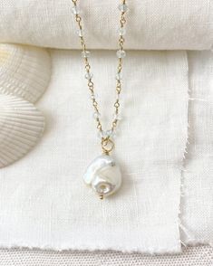 This elegant Baroque Pearl and Aquamarine Necklace is a luxurious statement piece featuring a large baroque pearl suspended on a chain of shimmering micro-faceted pale blue aquamarine gemstone beads, all handcrafted with beautiful gold fill. This coastal-inspired necklace is perfect for adding an elegant touch to any look, either solo or layered with other pieces. Necklace length: 16 inches plus 2 inch extender Materials: baroque pearl, aquamarine gemstone beads, gold filled clasp, wire and comp Elegant Baroque Pearl Teardrop Pendant Jewelry, Bohemian Pendant Necklace With Pearl Charm, Baroque Pearl Pendant Long Necklace, Bohemian Pearl White Jewelry With Pearl Drop, Long Baroque Pearl Necklace With Pearl Drop, Bohemian Pearl White Necklace With Pearl Charm, Teardrop Pearl Necklace With Pearl Chain, Bohemian Pearl Necklace With Pearl Charm, Elegant Baroque Pearl Round Pendant Necklace