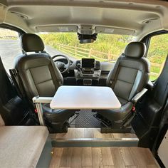 the interior of a van with tables and seats on it's back door area