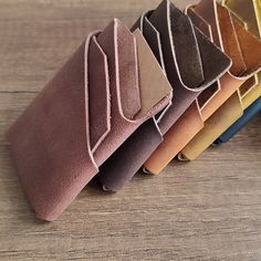 a row of different colored wallets sitting on top of a wooden table next to each other