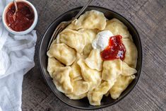 a bowl filled with dumplings and sauce next to a cup of ketchup