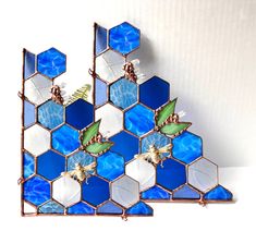 two blue and white hexagonal pieces with green leaves on them are shown in front of a white background