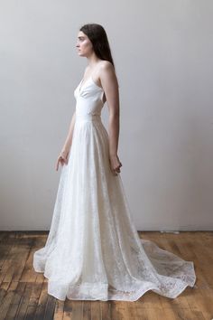 a woman in a white wedding dress standing on a wooden floor with her back to the camera