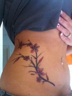 a woman's stomach with a tattoo on the side and flowers growing out of it