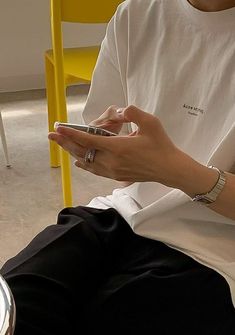 a person sitting in a chair holding a cell phone and looking at the screen with both hands