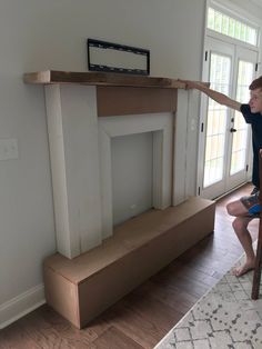 a young boy is sitting on a step ladder in front of a fireplace mantel