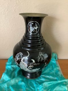 a black vase sitting on top of a blue cloth