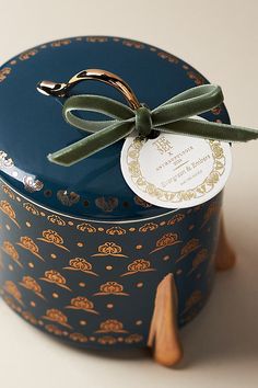 a small blue box with a green bow on it's top and label attached to the lid