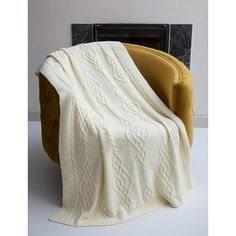 a white blanket sitting on top of a chair next to a fireplace