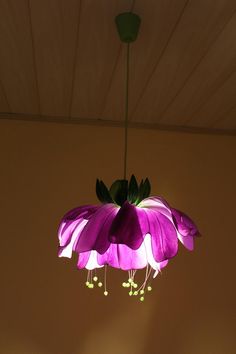 a purple flower hanging from the ceiling in a room with a light fixture above it