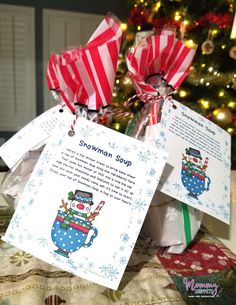 two christmas gifts wrapped in red and white paper sitting on top of a table next to a christmas tree