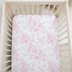 a pink and white floral print crib sheet in a baby's crib