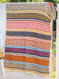 a colorful blanket hanging on the side of a building next to a potted plant