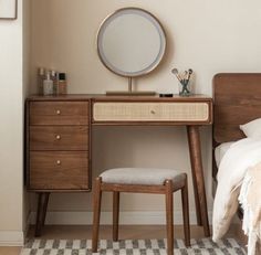 a bedroom with a bed, desk and mirror on it's side table in front of a window