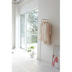 an empty room with clothes hanging on the wall and a potted plant next to it