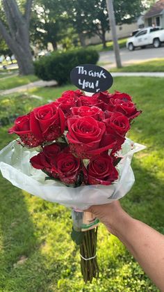 someone holding a bouquet of red roses with the words thank you written on it in front of them