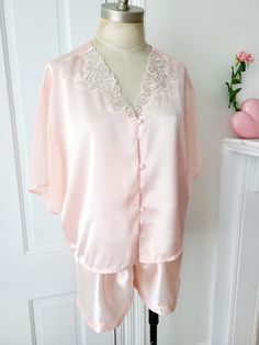 Vintage 2 piece pink satin pajama set. Top features sheer flowy sleeves and lace detail at neckline with tiny pearl accents. Pearl buttons. Elastic waistband on shorts. Excellent vintage condition.  Size: XL (see measurements) Material: poly satin Condition: excellent vintage  Label: Dora C.  //Measurements with item laying flat,  in inches// (Top) Shoulder: 19 Chest: 22 Length: 21 (Bottom) Waist: 12, stretches to 16 Hip:23 Inseam: 3 For best fit comparison, I suggest you measure a garment you own that you know fits you well and compare to measurements given here.  Alternatively you can take the bust, waist, and hip flat measurements from above and double them, then compare to your body measurements (including a little extra wiggle room depending on the fit you prefer).  All items are vint Vintage Ballet, Satin Pajama Set, Pyjama Satin, Satin Pajama, Flowy Sleeves, Ballet Pink, Satin Pyjama Set, Satin Pajamas, Vintage Labels