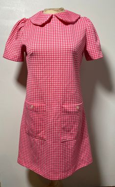 This pink gingham dress is so dreamy! It is handmade and from the 1960's, so totally one of a kind and in fantastic condition with no known flaws! It is closest to a size medium, but here are the exact measurements taken lying flat and doubled: Shoulders: 13 inches Chest: 36 inches Waist: 34 inches Hips: 36 inches Shoulders to Hem: 34 inches This dress is made from polyester and zips up the back to close. It has sweet little buttons on the front facing pockets. The collar is a Peter Pan style, r Vintage A-line Plaid Dress, Spring Retro Gingham Dress, Vintage Plaid Dress For Spring, Vintage Pink Dress For Picnic, Fitted Retro Plaid Dress For Spring, Retro Gingham Plaid Dress For Spring, Retro Gingham Dress For Spring, Retro Gingham Plaid Spring Dress, Retro Plaid Dress For Spring