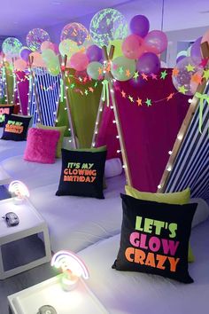 there are many balloons and decorations on the table in this room, including one that says let's glow crazy