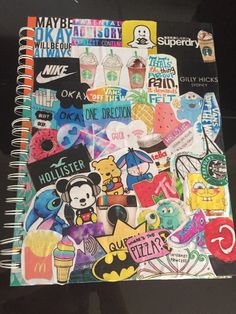 a notebook covered in lots of stickers on top of a black surface with writing underneath it