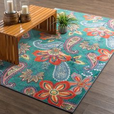 a rug with a wooden bench on the floor next to a potted plant and candles