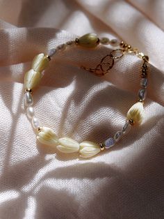 "Inspired by traditional Hawaiian leis gifted as tokens of hospitality, this handmade gold and pearl bracelet features a glistening collection of pearls, gold beads and pikake flower blossoms. Stack this gold pearl bracelet with other beaded beauties and you'll be ready for your tropical escape. ✦ DETAILS ✦ ✧ Name: Mele (MEH-leh) - Song. ✧ Adjustable Length from: 6.5\"-8\". ✧ 3-4mm Freshwater Pearl Beads. ✧ Carved Resin Pikake Beads ✧ 14kt Gold Filled Components, Extender, and Clasp. ✧ All Ke Al Bohemian Single Strand Beaded Bracelets As Gift, Elegant Yellow Flower Bracelets, Elegant Yellow Flower Bracelet, Handmade Cream Pearl Bracelet With Round Beads, Cream Beaded Pearl Bracelet As A Gift, Cream Beaded Pearl Bracelet Gift, Cream Beaded Pearl Bracelet For Gifts, Adjustable Pearl Bracelet With Large Beads As Gift, Flower Shaped Single Strand Jewelry For Gifts