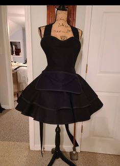 a mannequin with a black dress on display in front of a white door