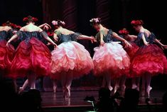 five ballerinas in tutu skirts on stage with their backs turned to the side