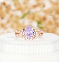 an engagement ring with a purple stone in the center on top of a white box