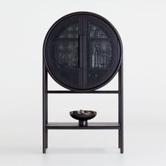 a black table with a bowl on it and a metal stand in front of it