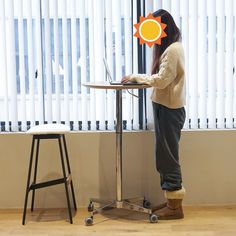 a woman standing in front of a table with a laptop computer on top of it