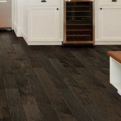 a kitchen with wood floors and white cabinets, an oven and wine rack in the center