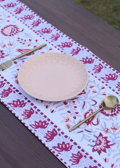 an empty plate on a table with gold spoons