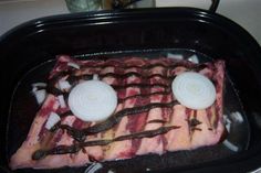 the meat is being cooked in the oven with onion slices and onions on it's sides