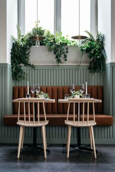 two wooden chairs sitting next to each other in front of a window with potted plants