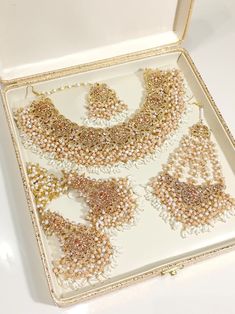 an open box with several pieces of jewelry in it on a white surface, including necklaces and earrings