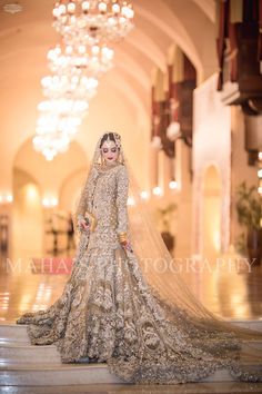 a woman in a bridal gown and veil standing on the floor with chandelier