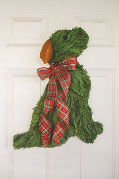 a door hanger made out of fake grass with a wooden duck decoration on it