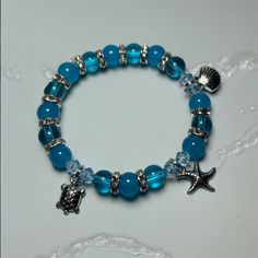 Dive into summer with our Unique Blue Summer Beach Themed Charm Bracelet! This stunning piece, featuring blue glass beads, measures approximately 7 inches and is designed to capture the essence of beach days and ocean waves. Whether you're lounging by the shore or enjoying a casual day out, this charm bracelet is the perfect accessory. It's an ideal gift for moms, friends, or any woman who loves unique and handmade jewelry. Perfect for stacking, this boho-chic, crystal-adorned bracelet adds a to Ocean Themed Gifts, Blue Bracelets, Ocean Bracelet, Pink Beaded Bracelets, Pony Bead Bracelets, Beads Candy, Beachy Jewelry, Blue Beaded Bracelets, Gems Bracelet